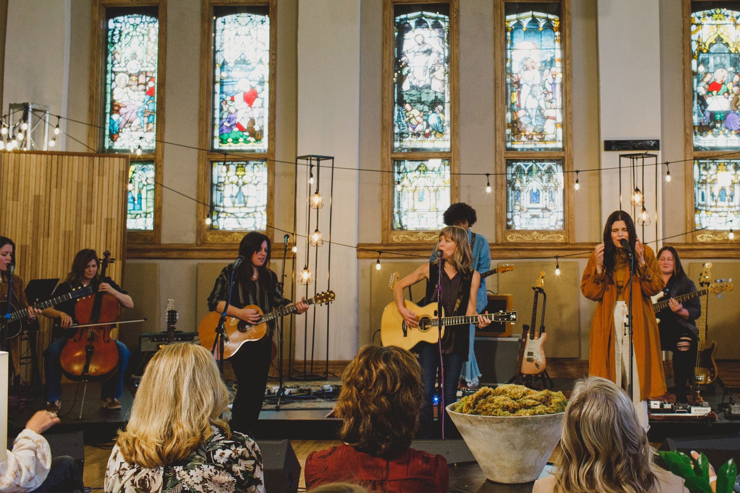 Band performs in front of stained glass windows.